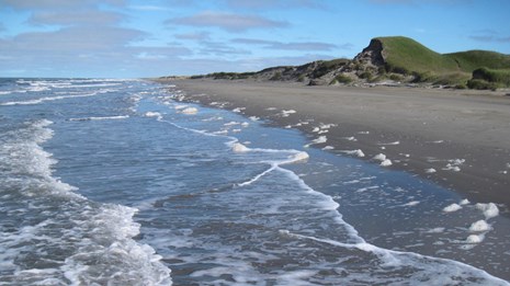 A long stretch of beach with gentle waves lapping the shore. 