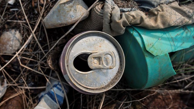 A pile of marine debris on the beach. An old metal can has the words, Don't litter, please recycle.