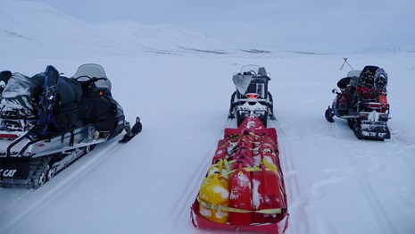 Three snowmobiles pointing down the trail. 