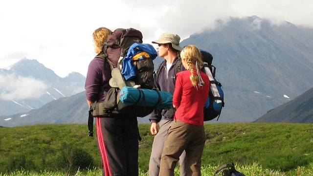 Three backpackers look out to the landscape. 