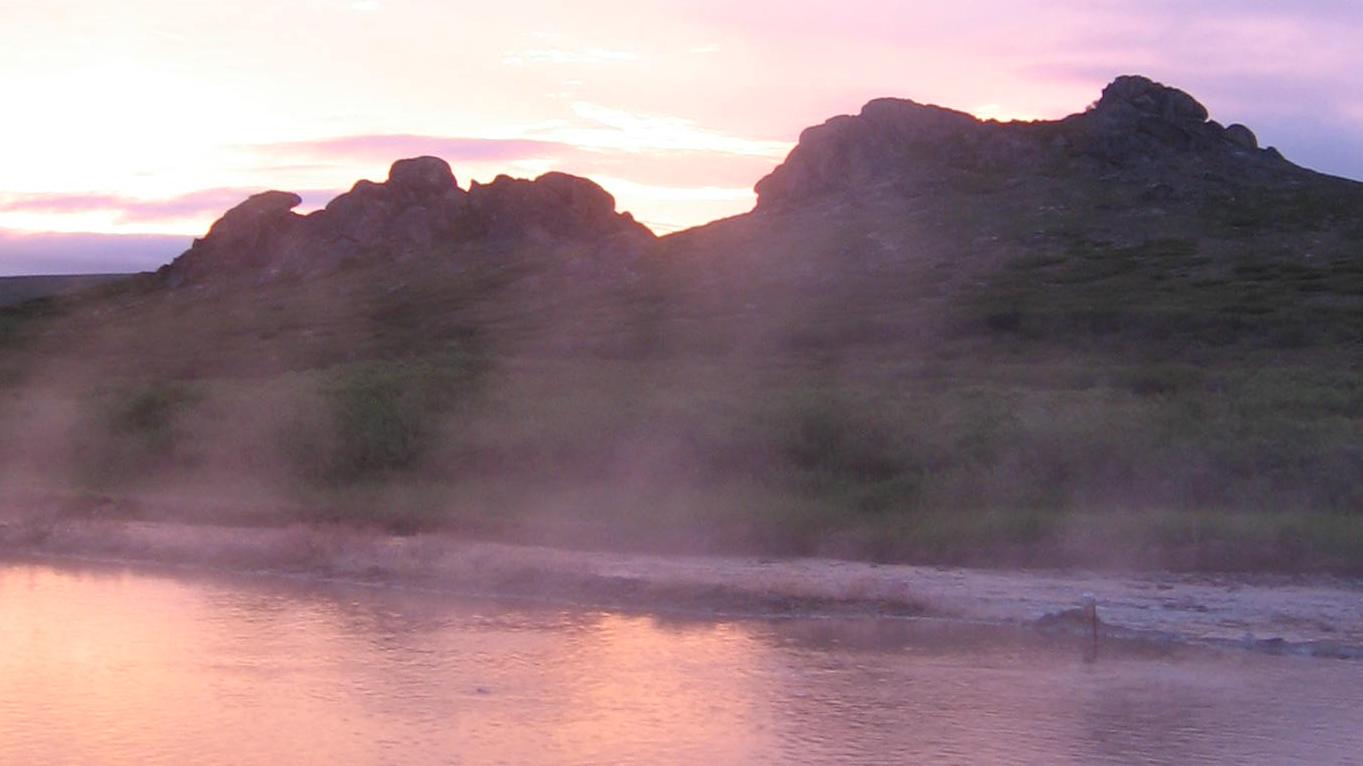 A small pool of water reflects a dusky sunset. 