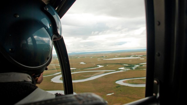A aircraft passenger looks out the window revealing views of a meandering river.