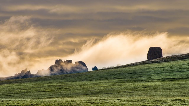 A cloud creeping across a ridge of granite tors.