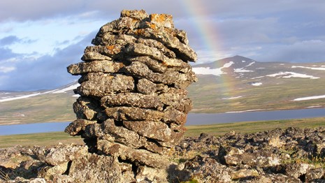 Rock cairn under rainbow
