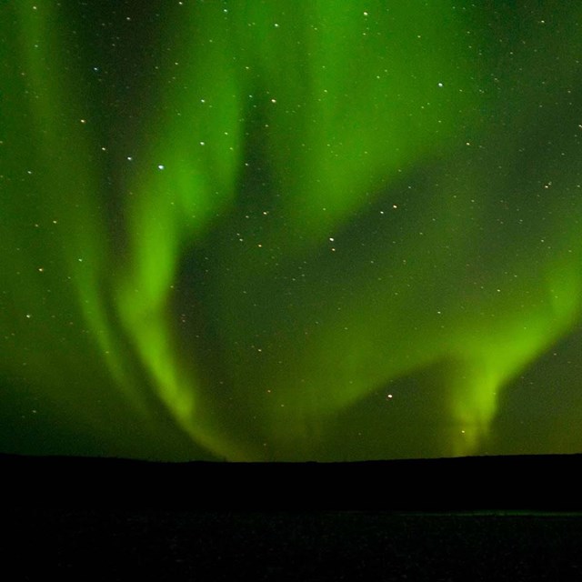 Green streaks of light fill the night sky.