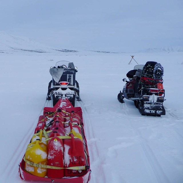 Three snowmobiles pointing down the trail. 