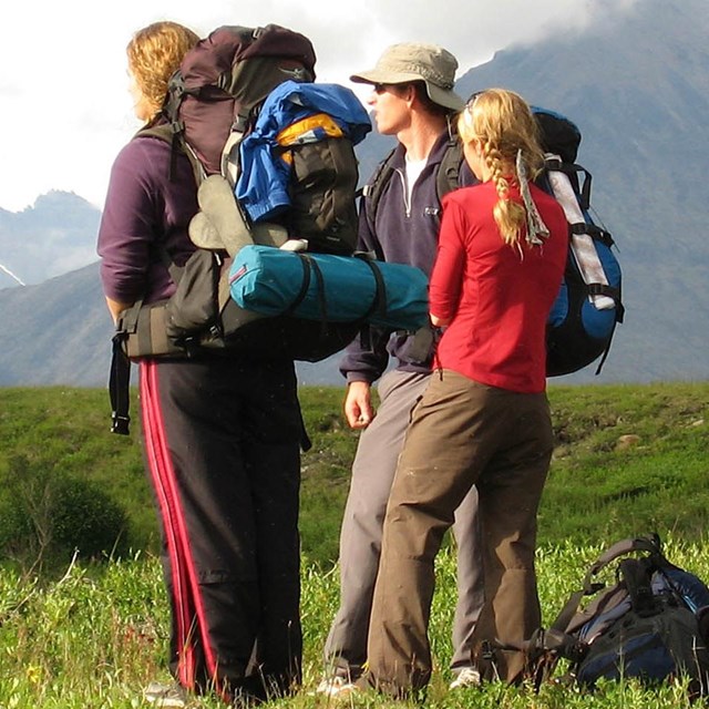 Three backpackers look out to the landscape. 