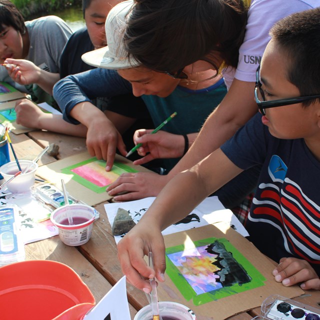 Kids watercolor painting outdoors.