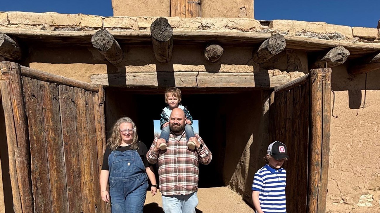 Family with two young children walks through fort entrance doors