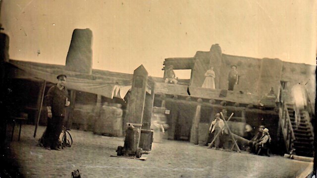 A modern tintype image showing people dressed in histoic costume within the reconstructed fort. 