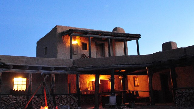 A nighttime view of the adobe fort with lanterns visible