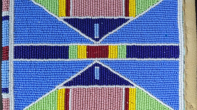 Crow-made deerskin pouch with brightly colored beads forming symmetrical geometric patterns