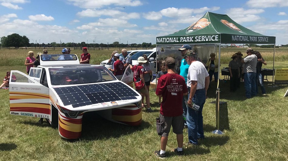 Solar cars with visitors and National Park Service tent