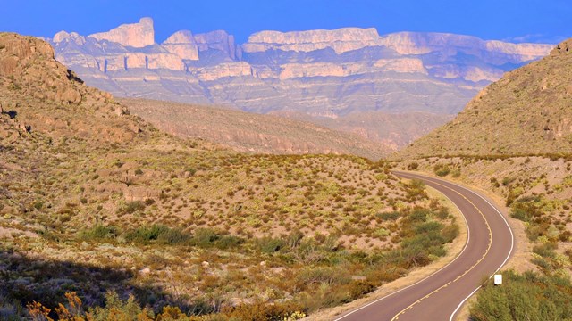 A paved scenic drive winds its way through rugged desert landscapes.