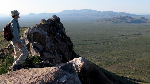 A hiker gazes into the vast desert and mountains of Big Bend.