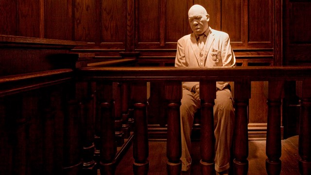 A statue of a African American man on the stand in a courtroom.
