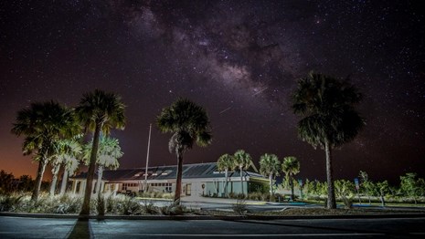 building and parking lot at night under a starry sky