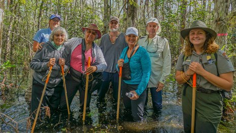 a ranger poses with a tour in knee deep swamp water