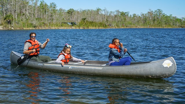 three people smile from a canoe