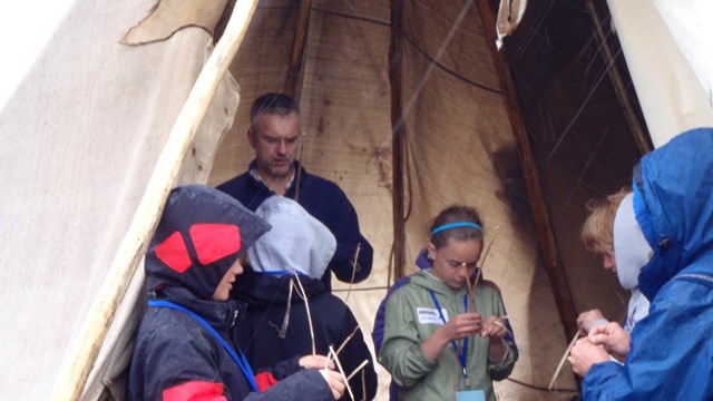 students in a tepee practice a skill with a cultural demonstrator during Coyote Camp