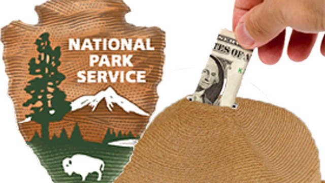 hand putting money into top of ranger hat with NPS logo