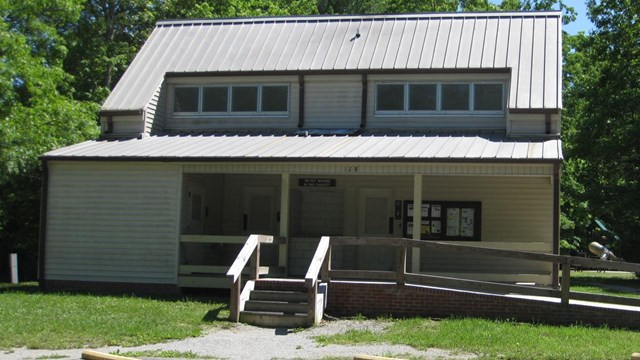 Bathhouse building with ramp and steps out into a parking lot