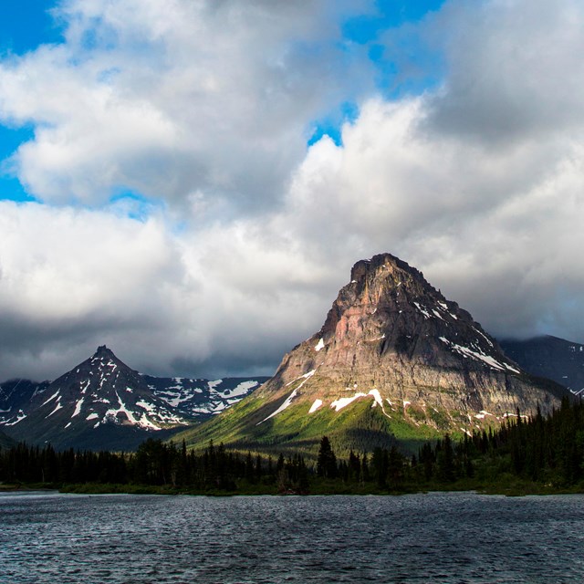 A tall mountain with a lake in the fore ground.