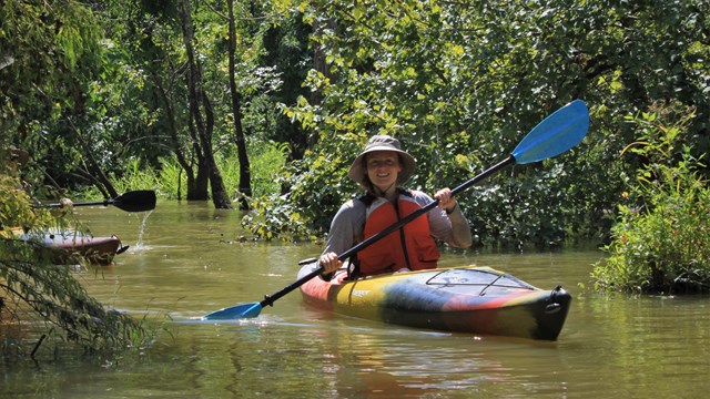 person kayaking on a small creek in the thicket