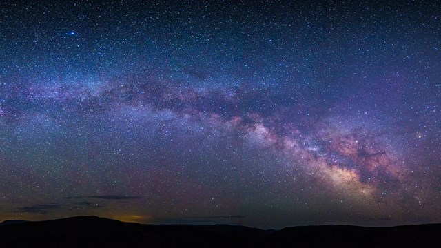 The Milky Way and a night sky full of stars glimmers over the Black Canyon of the Gunnison