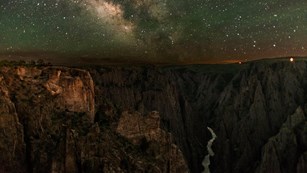 The Milky Way and a night sky full of stars glimmers over the Black Canyon of the Gunnison