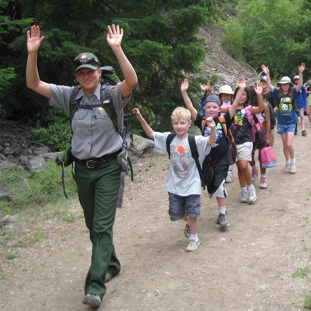 Students on a field trip hike on a trail led by a park ranger