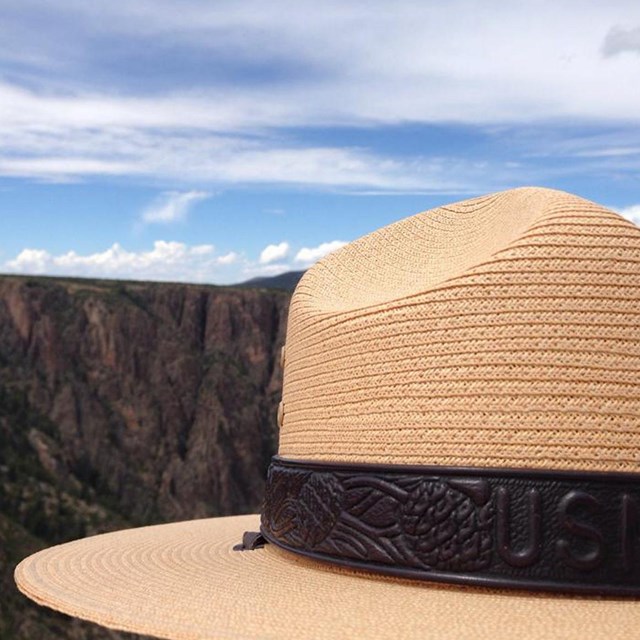 A woven park ranger hat with a canyon in the distance