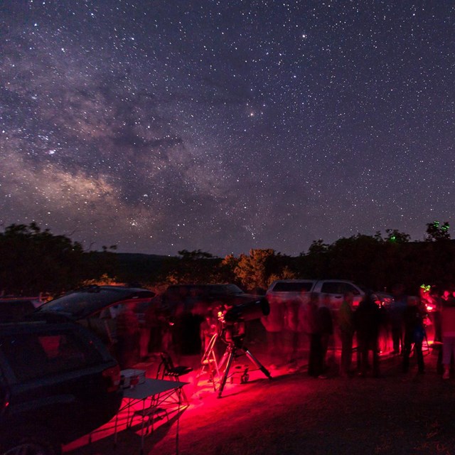 people around telescopes under a starry night sky