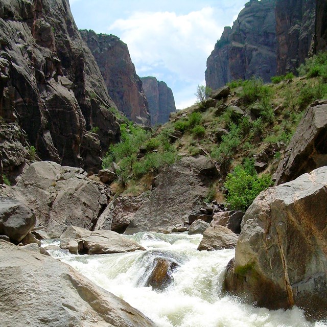A rushing river cascades through a deep, rocky canyon.