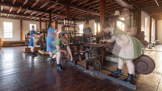 Women workers around textile machinery in wooden mill. Women are transparent