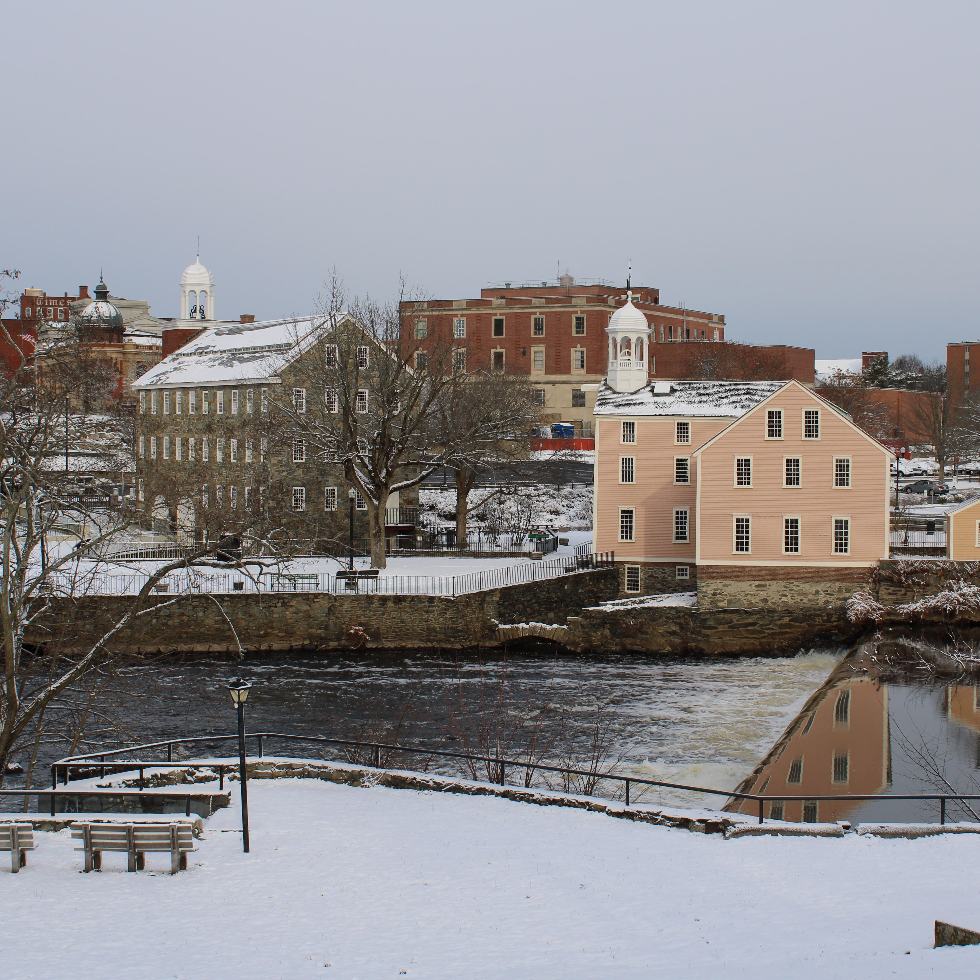 Yellow Mill building and stone building with dam in front and snow covering ground