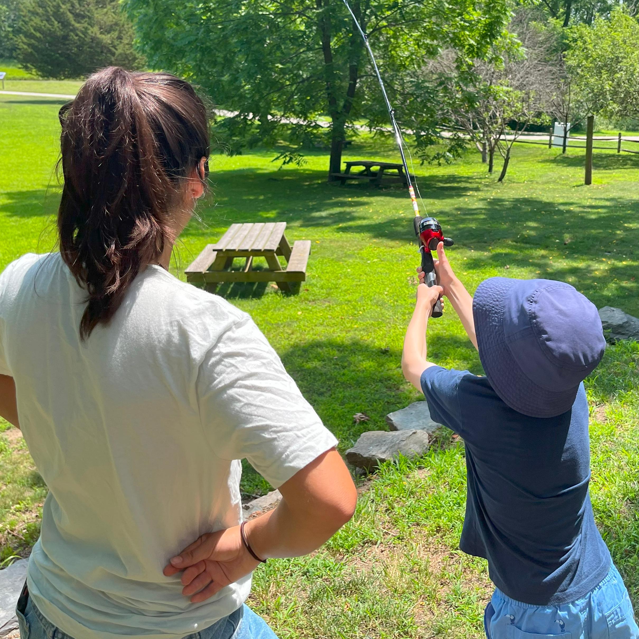 Intern and young angler practice casting with a fishing pole