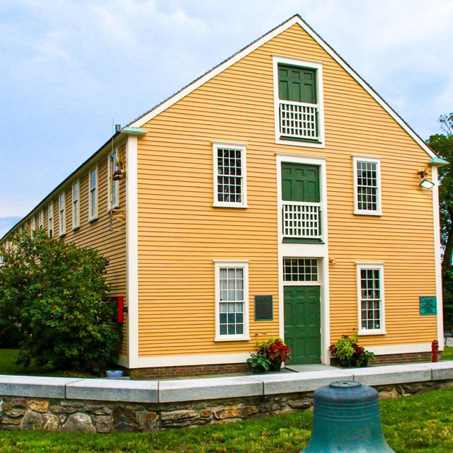 View of the bright yellow Slater Mill building