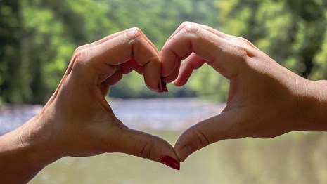 two hands form a heart over the river