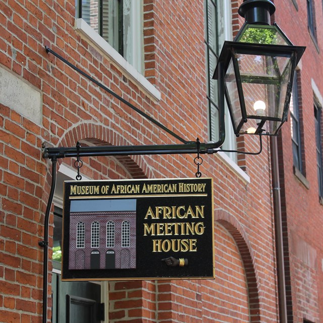 Exterior of brick building with lamp post and sign for the Museum.