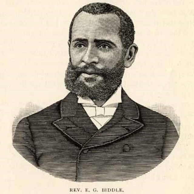 Portrait of Biddle who has short hair and a beard wearing a dark coat