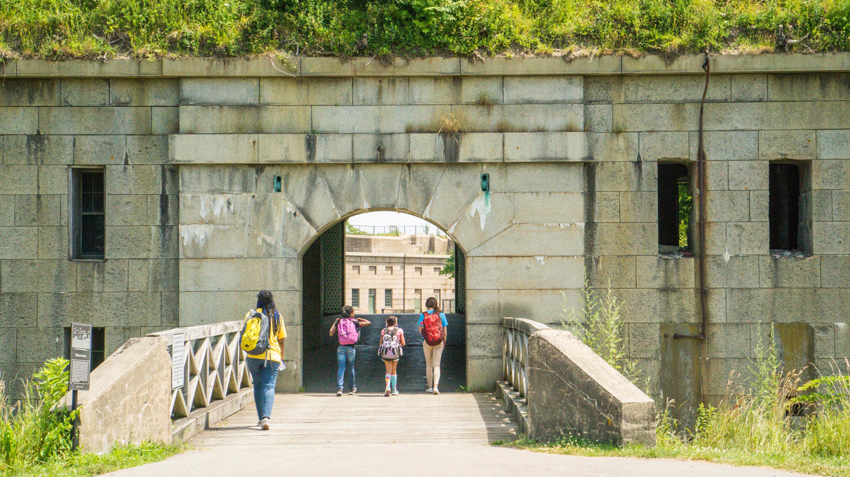 Bridge and entrance to a fort with greenery on top of the stone.