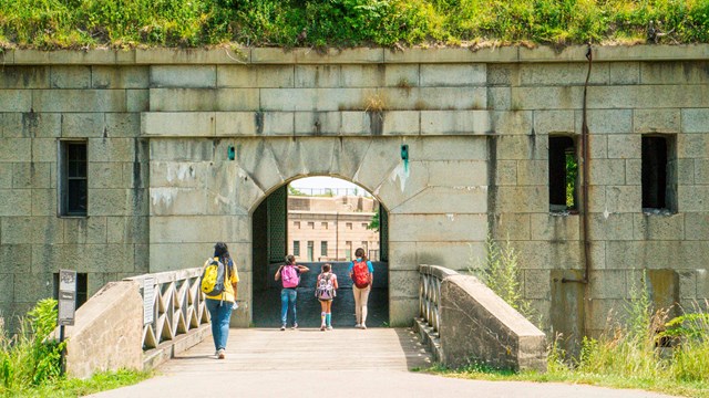 Bridge and entrance to a fort with greenery on top of the stone.