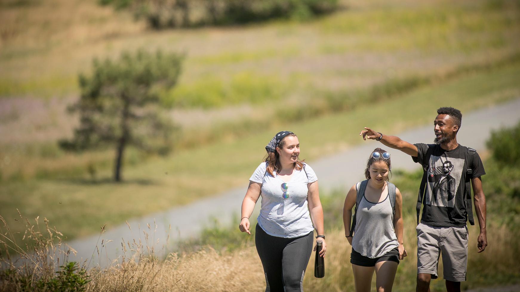 Three walkers (one man and two women) on a trail at Spectacle Island.
