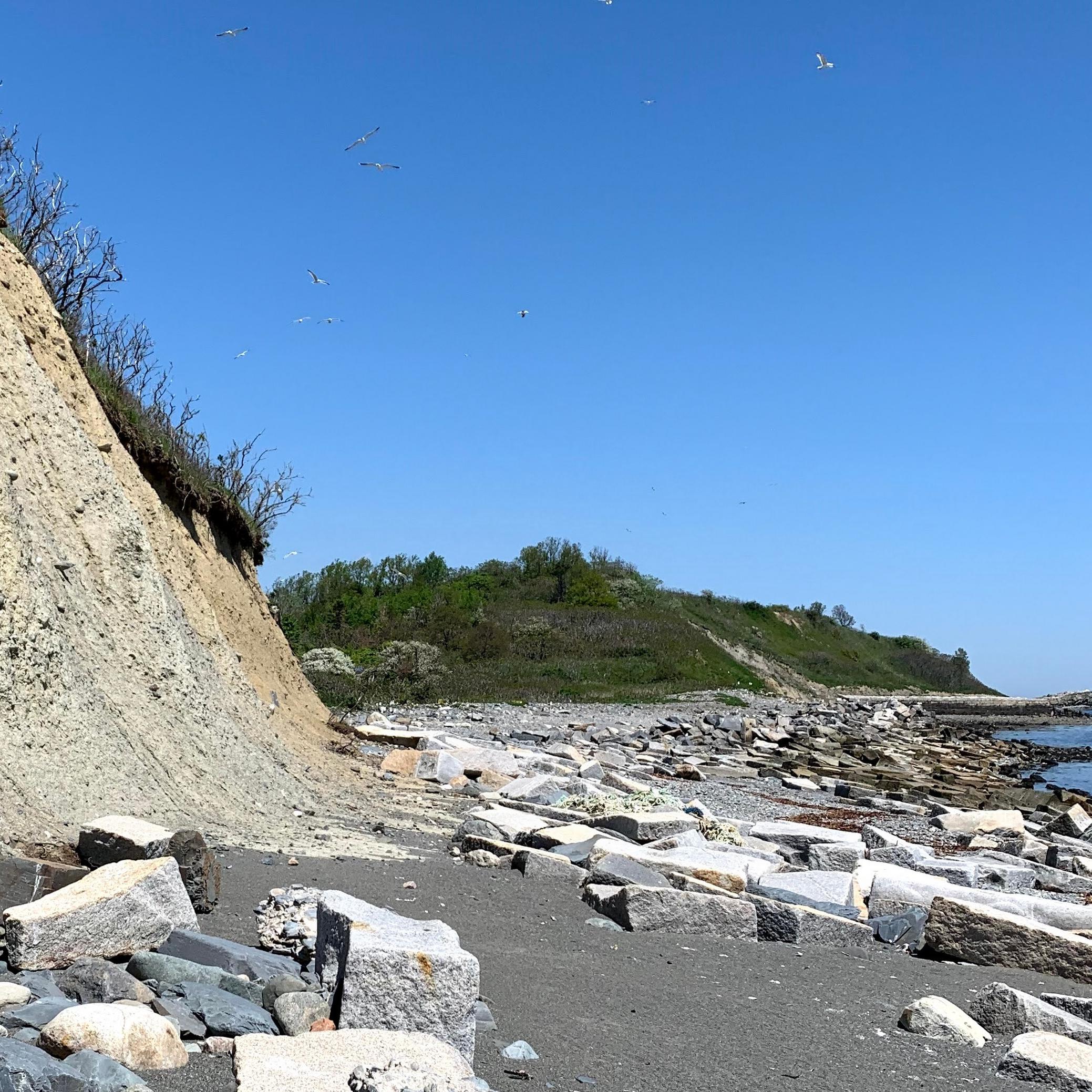 a rocky beach next to an eroding sandy bluff.