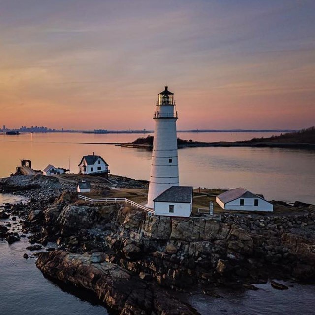 An island with a white lighthouse during a sunset