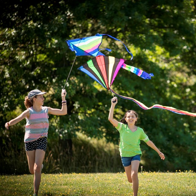 Two girls running with kites