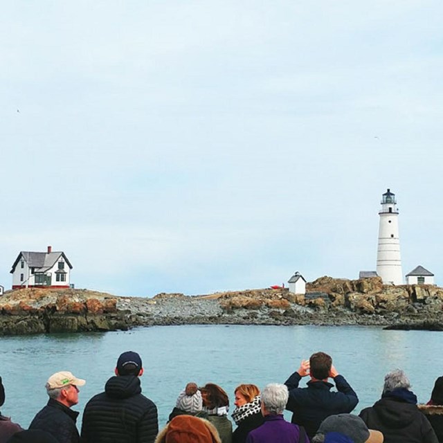 cruise-goers taking pictures and looking at Boston Light.