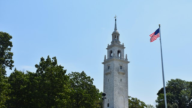 Dorchester Heights Monument with a flag pole to the right waving an American Flag.