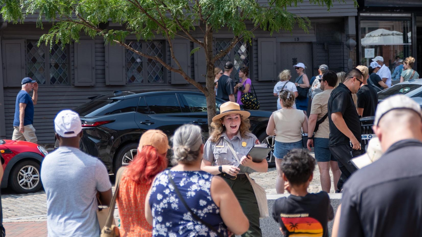 A ranger giving a talk to a group of visitors in a small plaza in front of Paul Revere's House.